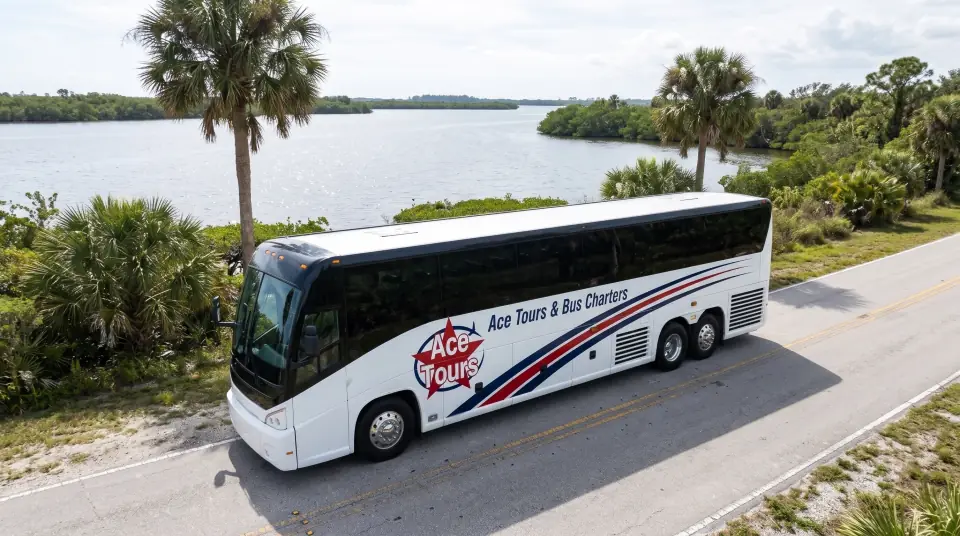 Illustration of a white Ace Tours & Bus Charters motorcoach on a road beside the wide St. Lucie River in Port St. Lucie, mangroves and palms on the bank, seen from a low drone angle
