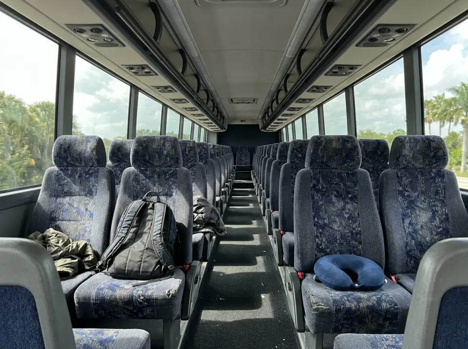 Illustration of the empty aisle of a modern motorcoach with travel pillows and backpacks left on the seats, daylight through tinted windows