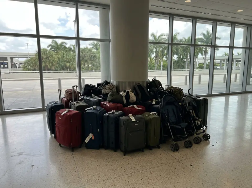 Illustration of a large group's suitcases, strollers and carry-on bags gathered around a column in a bright airport arrivals hall