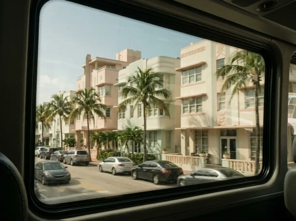 Illustration of Miami Beach Art Deco buildings seen through the large tinted side window of a motorcoach, with the window frame visible