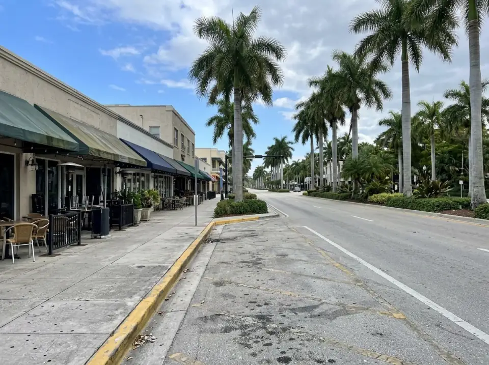 Illustration of a palm-lined downtown Fort Lauderdale boulevard with restaurant awnings and an empty curbside loading zone
