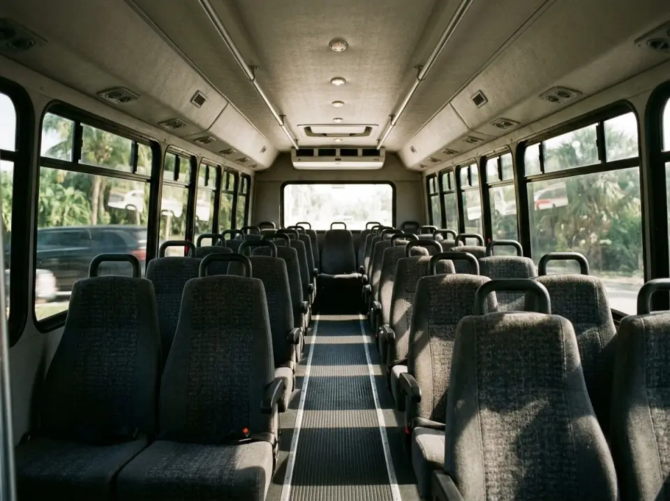 Illustration of the clean, empty interior of a minibus with high-back seats on both sides of a center aisle and tinted windows