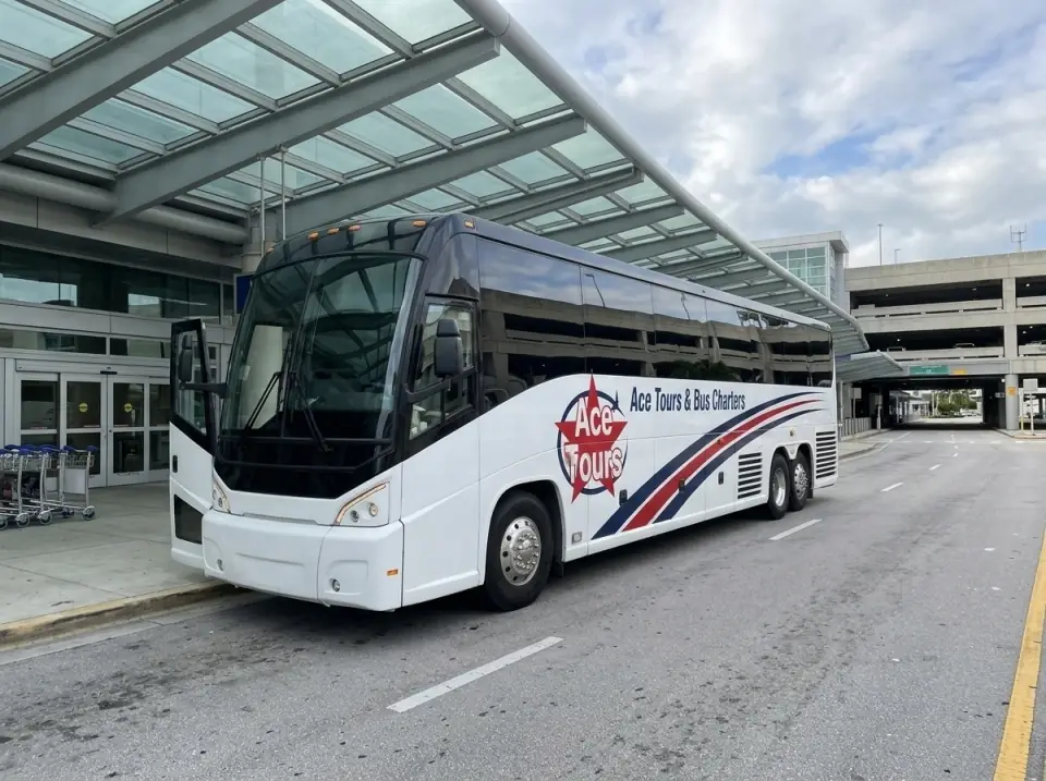 Illustration of a white Ace Tours & Bus Charters motorcoach at a large airport departures curb under a long glass and steel canopy, door open