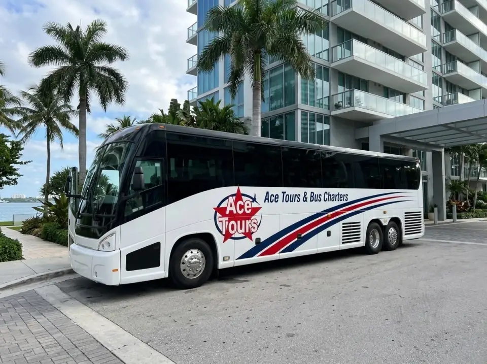 Illustration of a white Ace Tours & Bus Charters motorcoach waiting at the curb of a Miami condo tower, door open, royal palms and Biscayne Bay behind