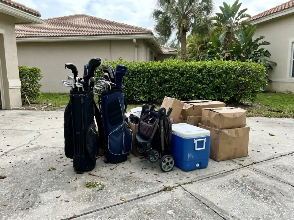 Illustration of two golf bags, a folded stroller, a blue cooler and cardboard boxes waiting together on a South Florida driveway