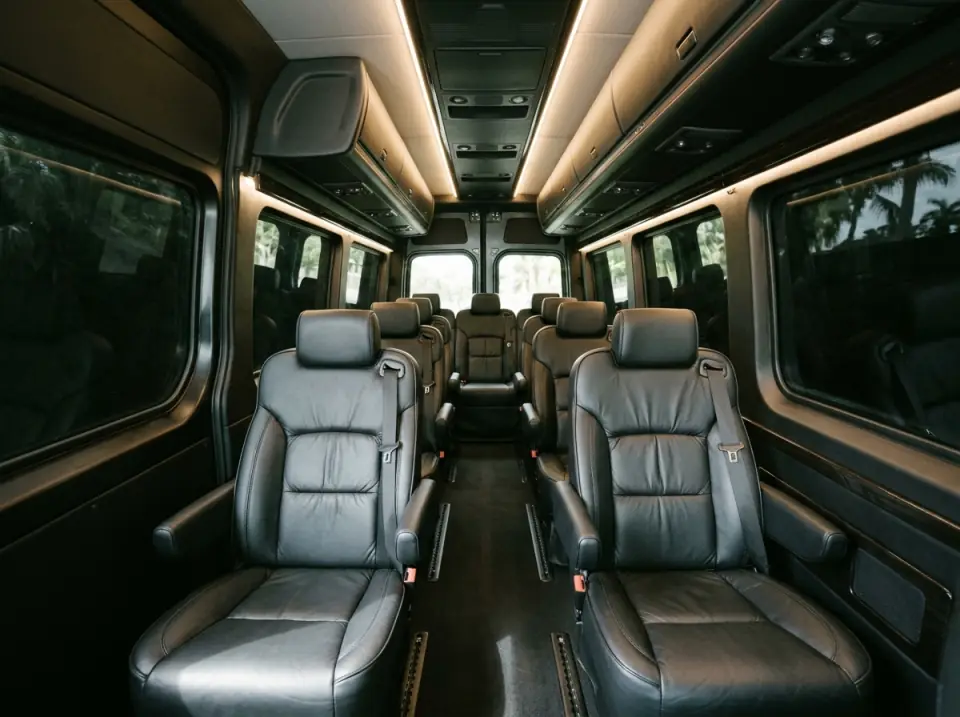 Illustration of the empty interior of a high-roof passenger van with rows of black leather captain's seats, ceiling lights and tinted windows