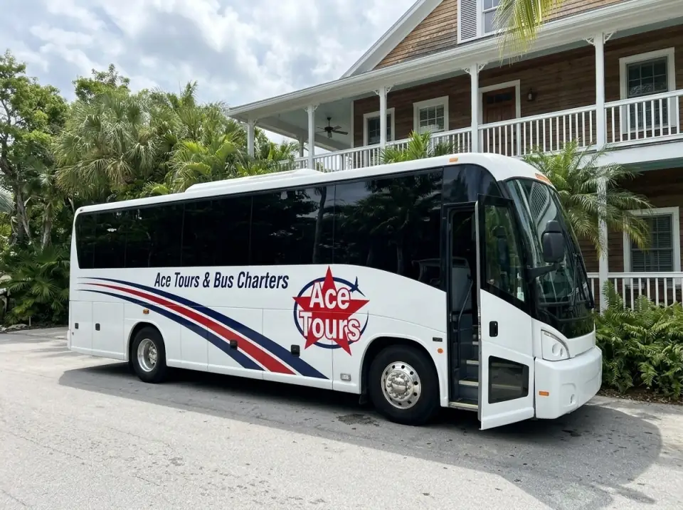 Illustration of a white Ace Tours & Bus Charters coach waiting with its door open beside a Key West inn with a wide porch, white railings and palms