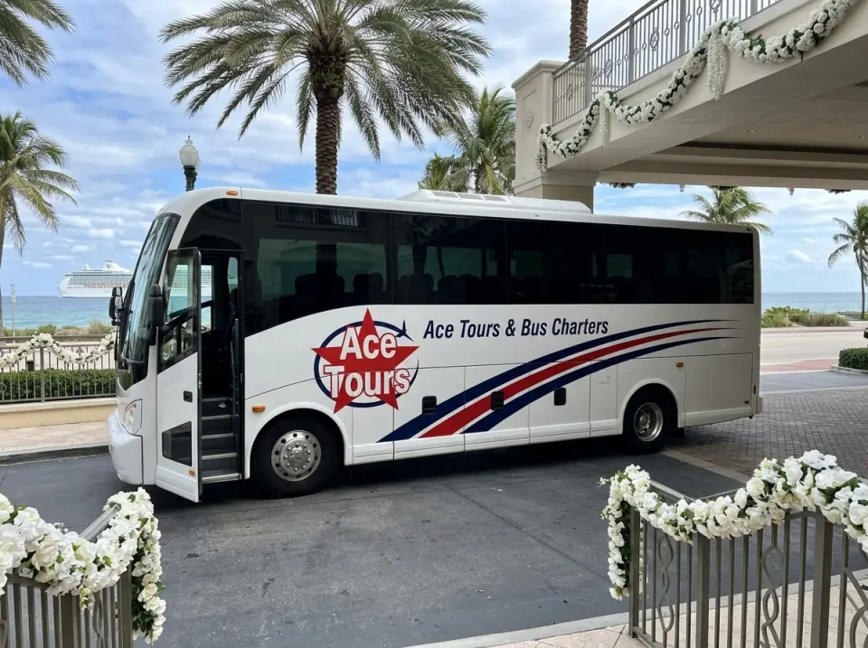 Illustration of a white Ace Tours & Bus Charters coach waiting at a Fort Lauderdale beachfront hotel entrance with its door open and white flower garlands on the railing