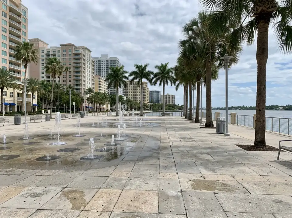 Illustration of the West Palm Beach downtown waterfront, with a splash fountain plaza, a palm-lined promenade along the Intracoastal Waterway and mid-rise towers